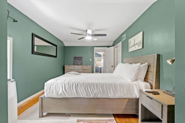 Cozy bedroom with a green wall, white bedding, and modern furnishings.