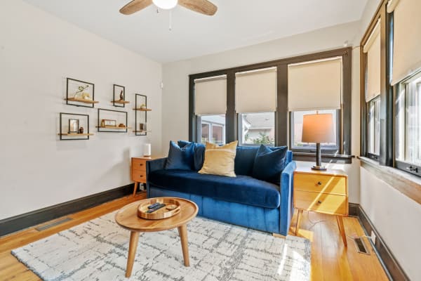 Cozy living room with blue couch, side table, lamp, and decorative shelves.