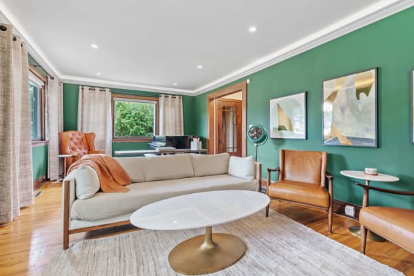 Chic living room featuring a green accent wall, cozy sofa, and elegant art pieces.