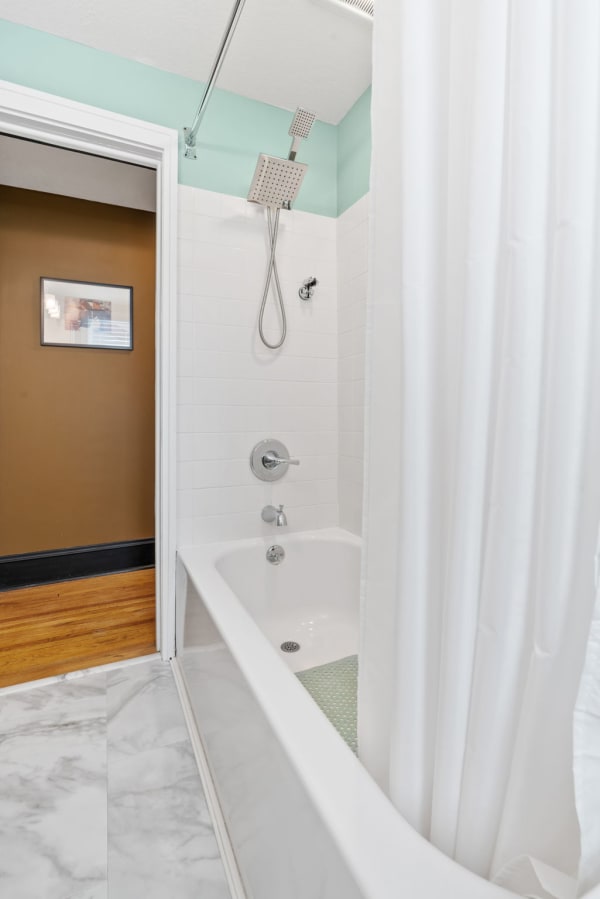 Modern bathroom with white tub and mint green accents.
