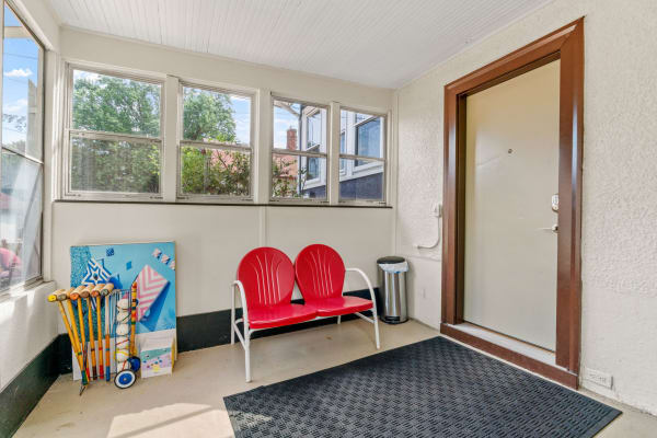 A bright entryway with red chairs and croquet equipment leaning against the wall.