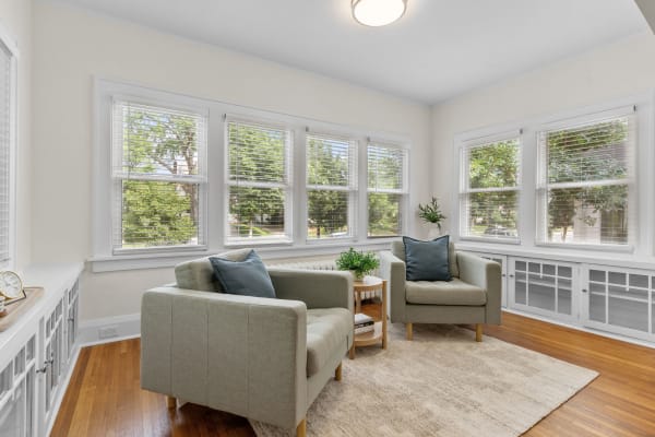 Bright sitting area with two armchairs and windows showcasing greenery outside.