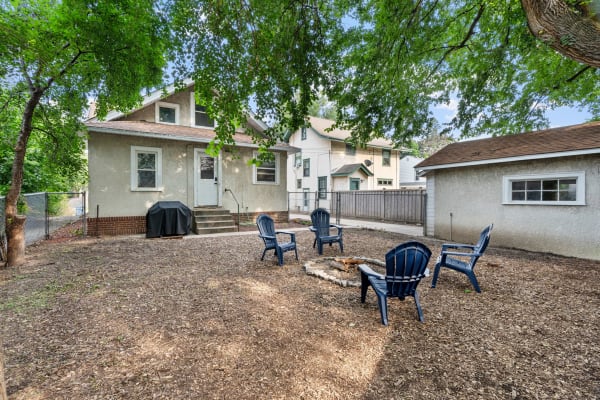 Backyard with a fire pit and seating surrounded by trees and homes.