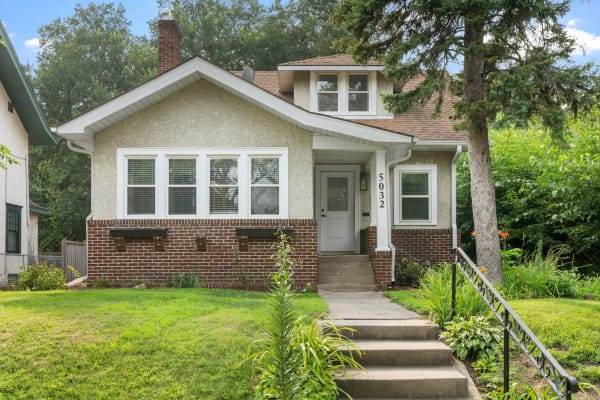 A picturesque home featuring brick and plaster exterior with a green yard.