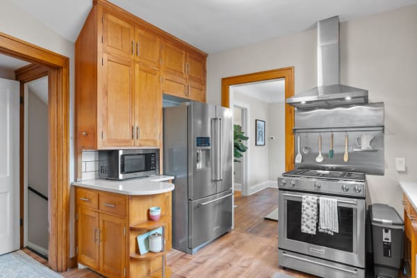 Modern kitchen with wooden cabinetry, stainless steel refrigerator and gas stove.