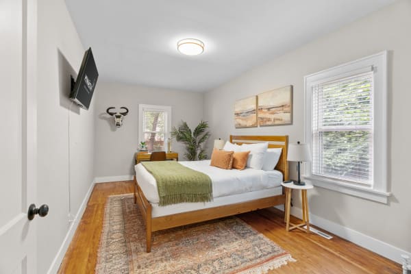 A warmly decorated bedroom with a wooden bed, green blanket, and a decorative antler mount.
