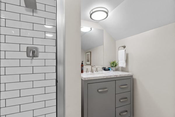 A stylish bathroom featuring a walk-in shower with subway tiles and a marble-topped vanity.