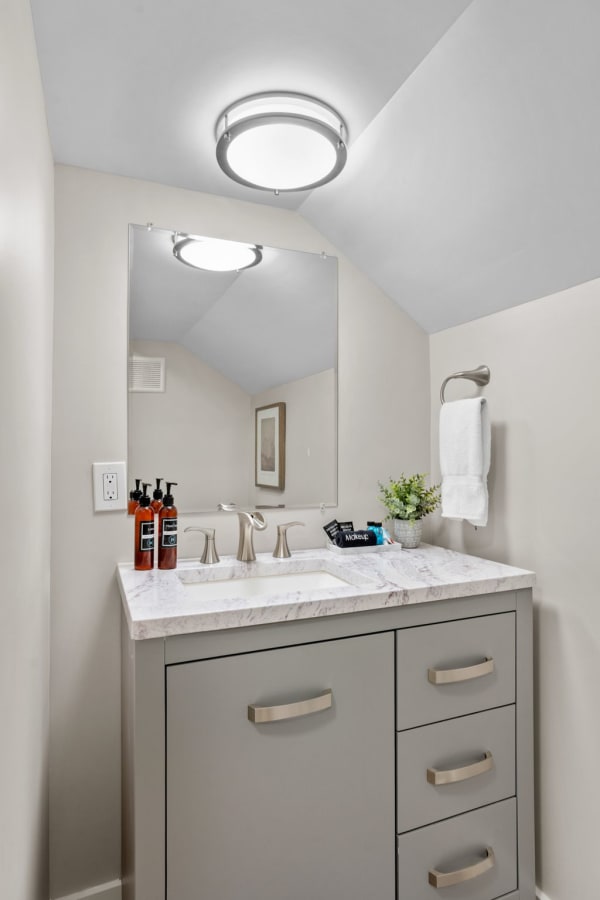 Modern bathroom with marble countertop and contemporary fixtures including a mirror and stylish accessories.