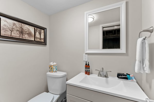 A contemporary bathroom featuring a white vanity, mirror, and decorative wall art.