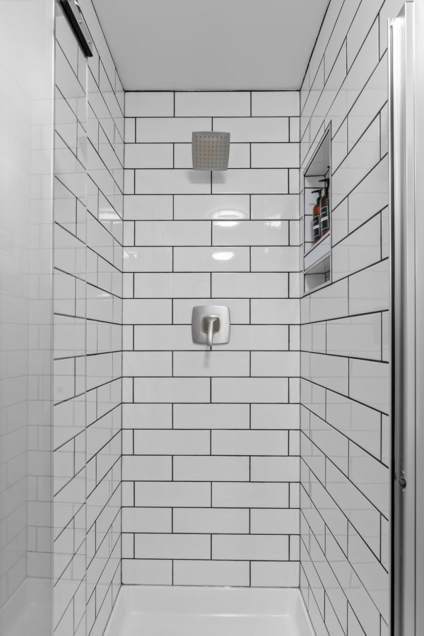 Interior view of a minimalist shower with white subway tiles and a modern showerhead.