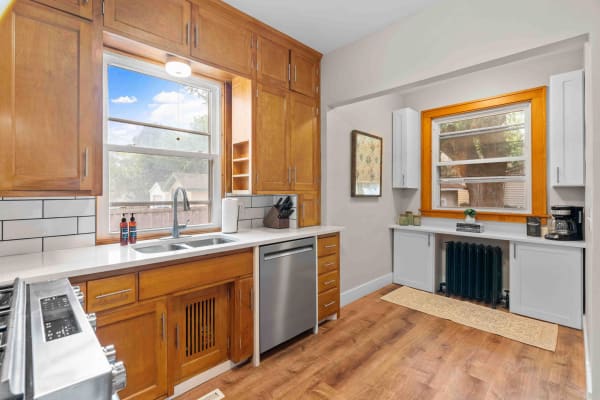 Modern kitchen featuring wooden cabinets, stainless steel appliances, and natural light from a window.
