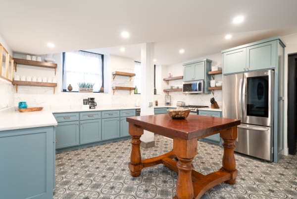 Modern kitchen featuring blue cabinets, a wooden island, and patterned tile floor.