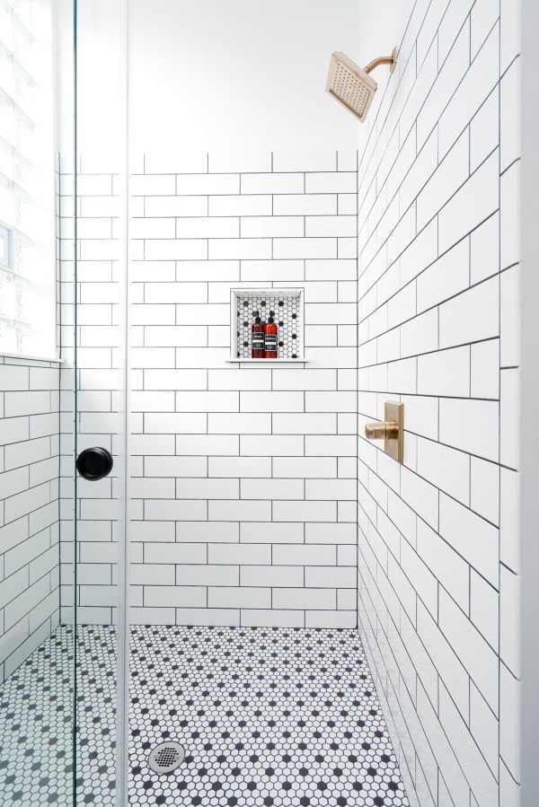 Modern shower with white subway tiles and hexagonal mosaic flooring.