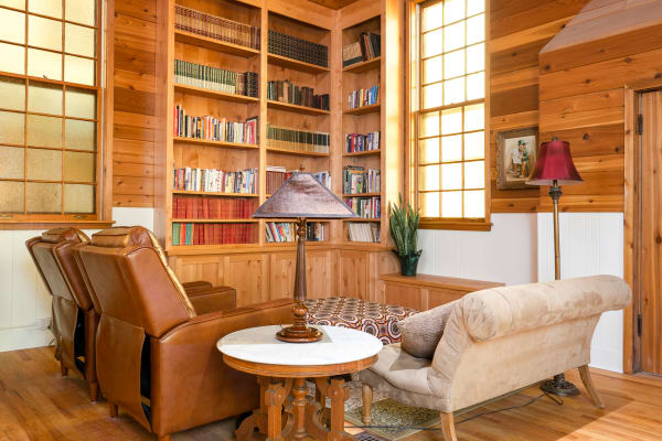 A comfortable library corner with leather chairs, a round table, and a collection of books.