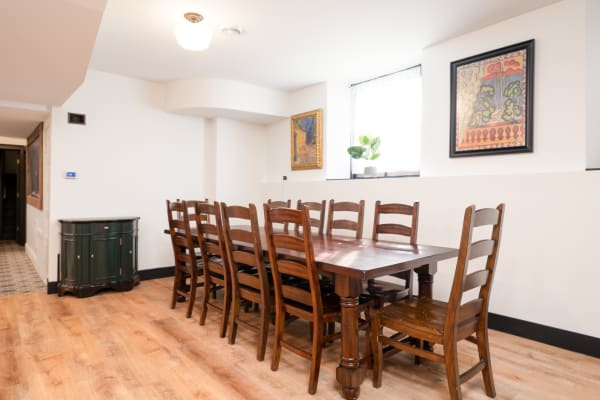 Long wooden dining table with chairs in a bright room with artworks on the walls.