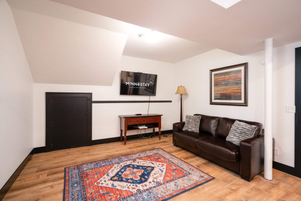Cozy living area with a leather sofa, decorative rug, and framed art on the wall.