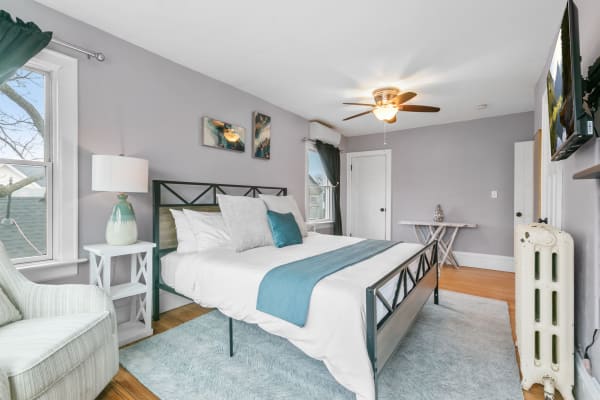 A modern bedroom with gray walls, a metal bed frame, and turquoise accents.
