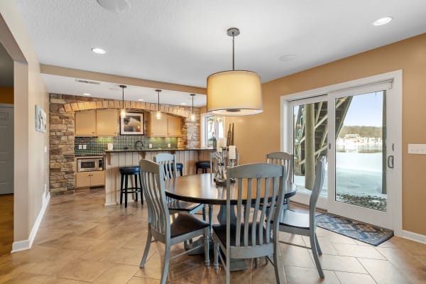 A kitchen with a dining table, modern lighting, and a view of a snowy landscape.