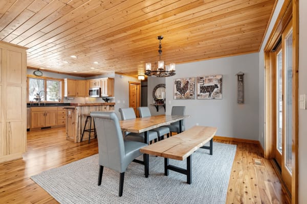 Inviting dining area with wooden ceiling, rustic dining table, and gray chairs.