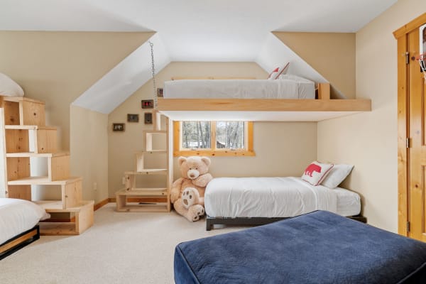 A children's bedroom with a bunk bed, white bedding, and a large teddy bear.