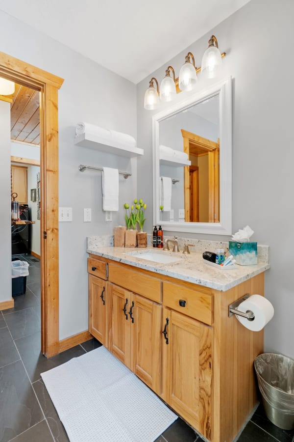 Contemporary bathroom featuring wooden vanity, stylish lights, and fresh flowers.