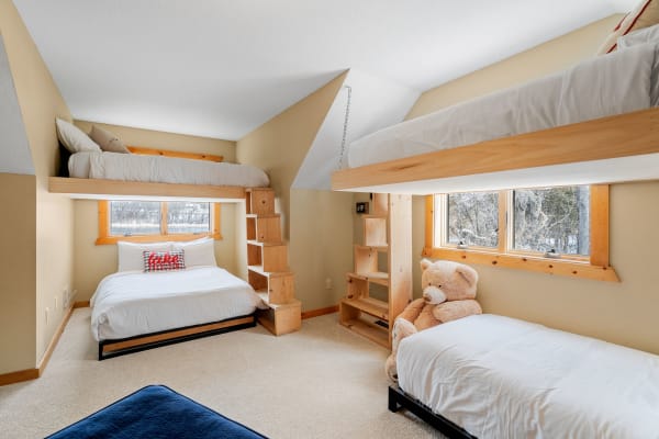 A cozy bedroom featuring a bunk bed, a single bed, and a plush teddy bear.