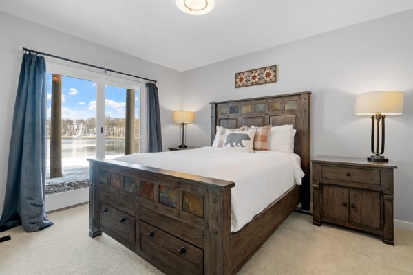 Cozy bedroom with wooden furniture and lake view through sliding doors.