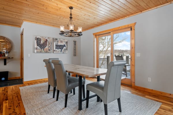 An inviting dining room featuring a wooden table and gray chairs, with a chandelier and sliding glass door to the outside.