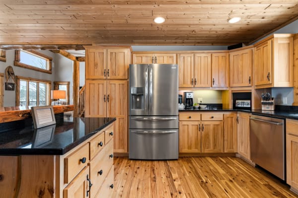 Modern kitchen featuring wooden cabinets, a silver refrigerator, and a rustic wooden floor.