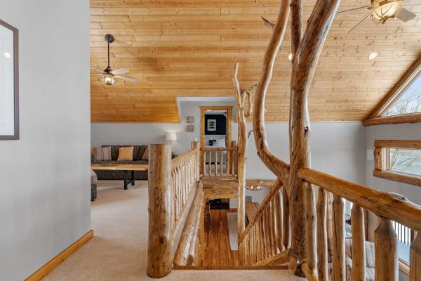 Interior view of a rustic loft area with wooden railings and comfortable seating.