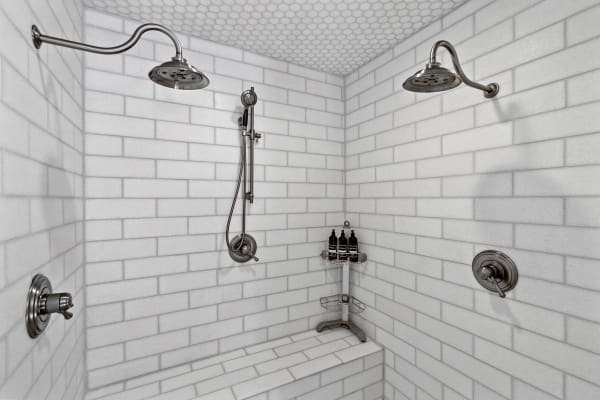 Modern shower space with white tiles and chrome fixtures.