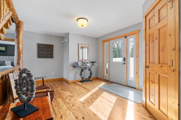 Bright foyer with wooden flooring and decor including a sculpture and mirror.