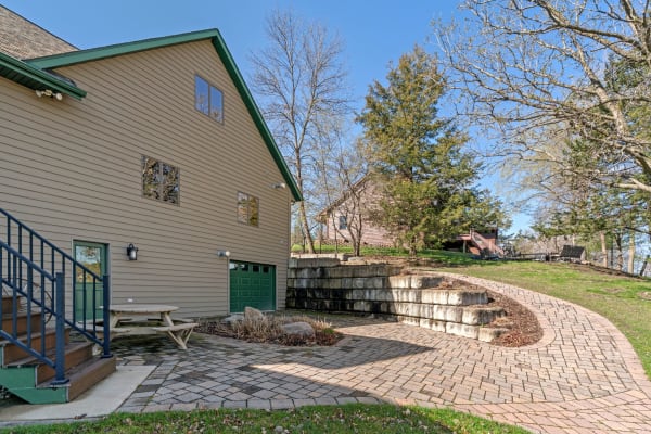 View of a modern home with light brown siding, green roof, and landscaped garden area.