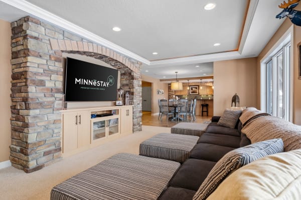 Inviting living room with a sectional sofa, stone wall, and modern television.
