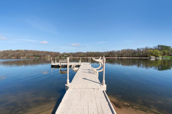 A dock stretching into a calm lake with clear blue skies and reflections on the water.