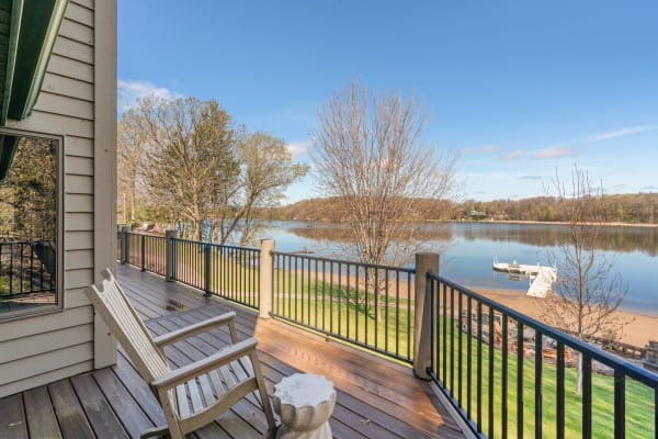 Lakeside view from a wooden deck featuring a chair and a calm lake.