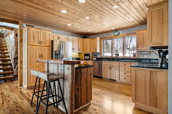 A cozy kitchen with wooden cabinets, granite countertops, and a view of outside trees.