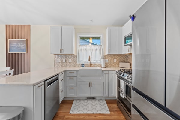 Interior of a stylish kitchen featuring gray cabinets, a farmhouse sink, and contemporary appliances.