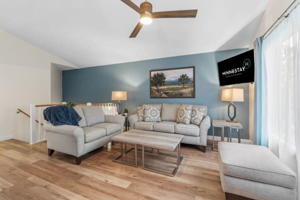 Living room with gray sofas, a wooden coffee table, and blue accent wall, featuring a TV displaying a logo.