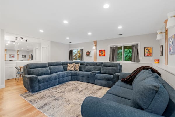 Modern living room with a blue sectional sofa, wooden flooring, and wall art.
