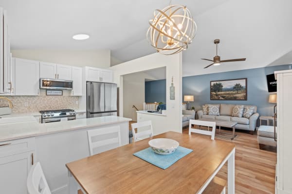 Contemporary kitchen and living room with white cabinets, stainless steel appliances, and cozy seating area.