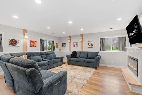 Modern living room with dark blue couches, artwork, and an electric fireplace.