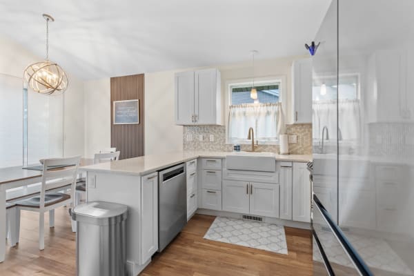 Modern kitchen with white cabinets, farmhouse sink, and a cozy dining area.