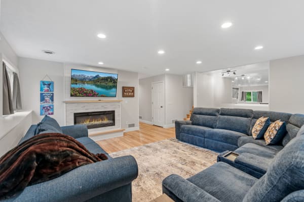 Spacious living room featuring blue couches, a stone fireplace, and a large television displaying a scenic view.