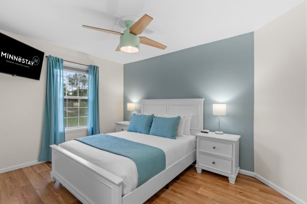 Cozy modern bedroom with light blue accent wall, double bed, and flat-screen TV.