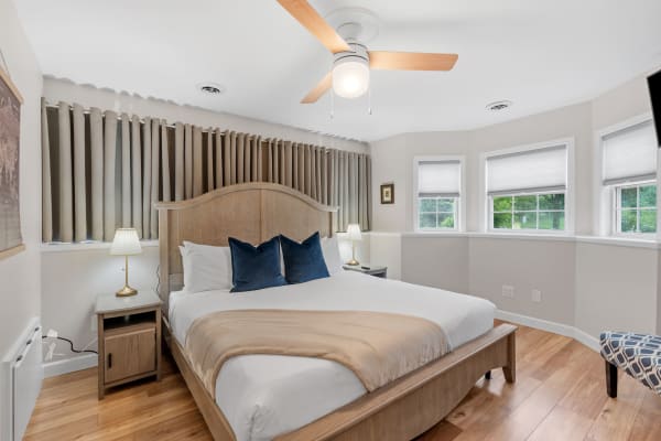 Cozy and inviting bedroom featuring a bed, bedside table, and windows.