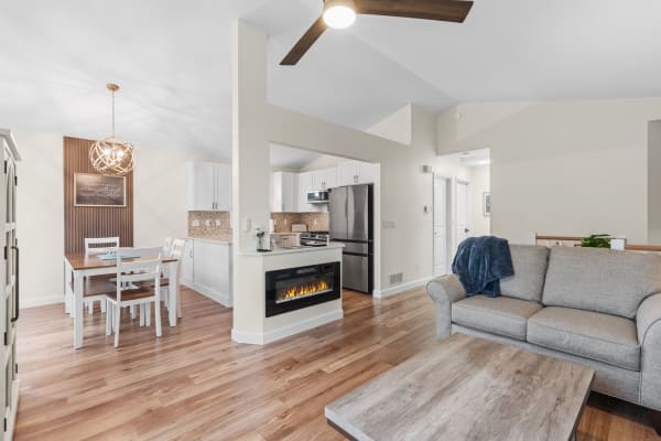 Modern living area with dining table, kitchen appliances, and gray sofa.