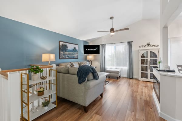 Modern living room with a gray sofa, blue walls, and wooden flooring.