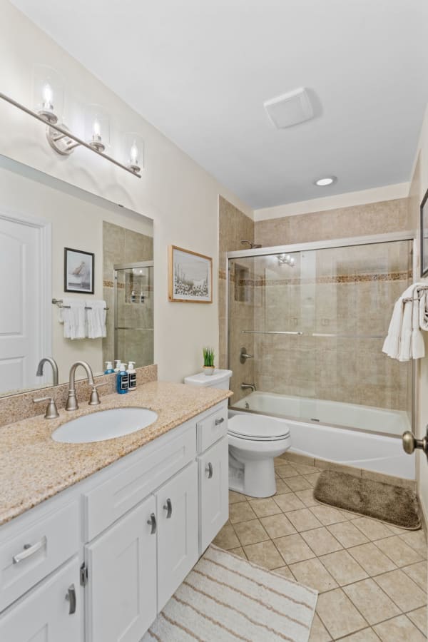 Modern bathroom featuring a granite countertop, white cabinets, and a glass shower.