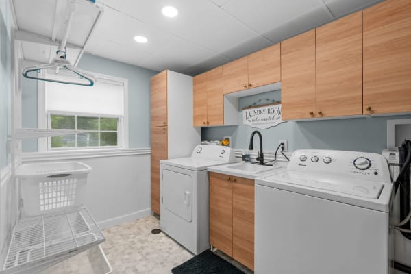 Modern laundry room with white appliances and light blue walls.